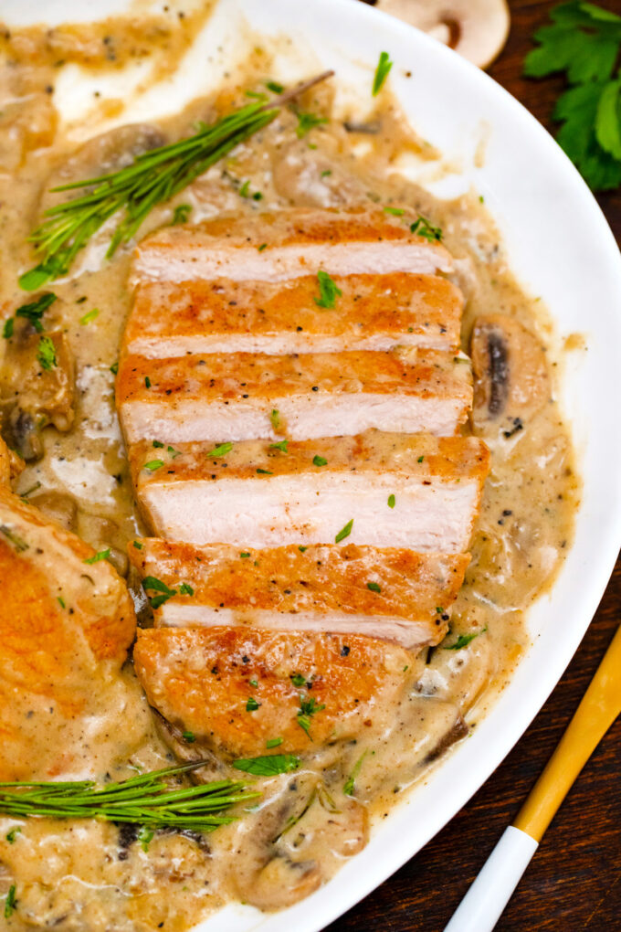 Sliced creamy mushroom pork chops with fresh rosemary.