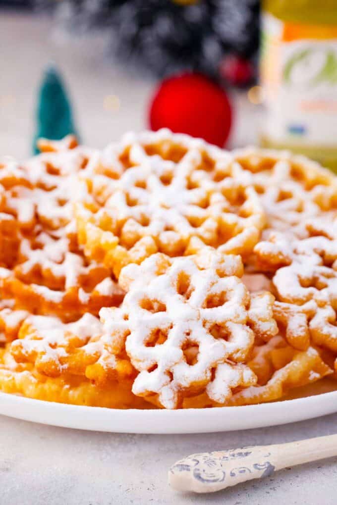 a plate with classic rosette cookies covered in powdered sugar