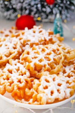 rosette cookies covered in powdered sugar next to a Christmas wreath