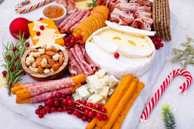 overhead shot of santa claus cheese board with christmas tree shaped cheese Santa Claus shaped cheese fruits and dips