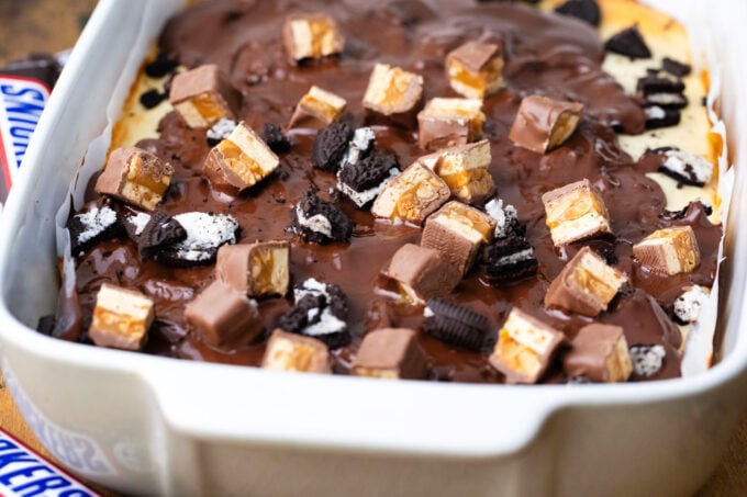 Slutty cheesecake brownie bars topped with Snickers candy.