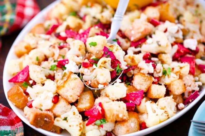 winter panzanella salad with pink radish and a serving spoon in it