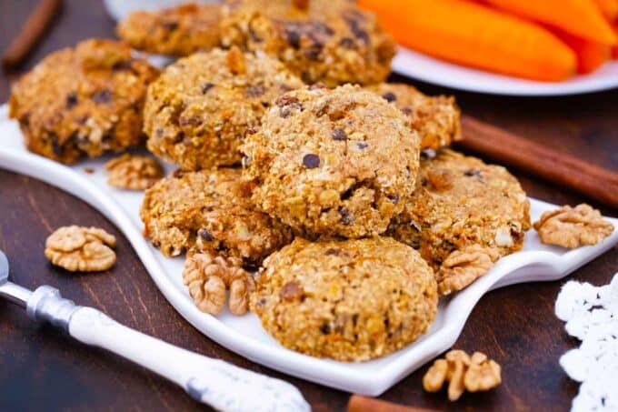 a plate of carrot oatmeal cookies with carrots in the background