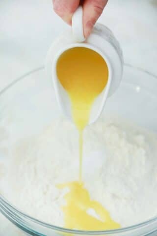 pouring melted butter over flour