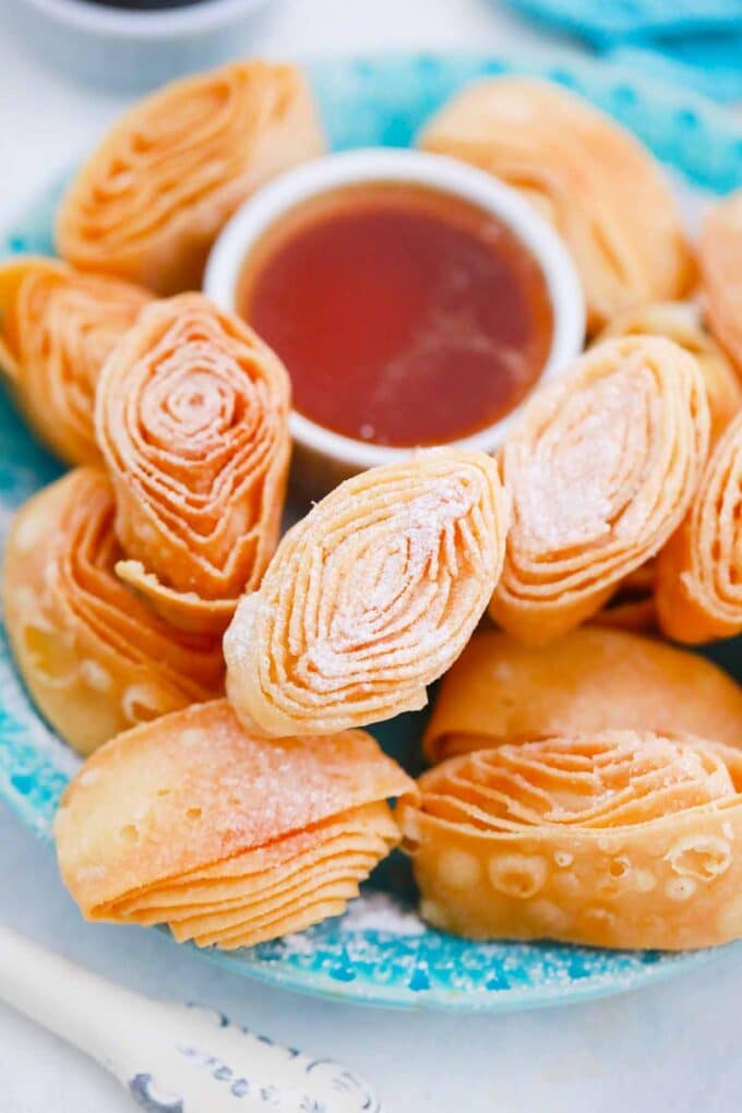 a plate with fried dough roses and a sauce bowl with caramel