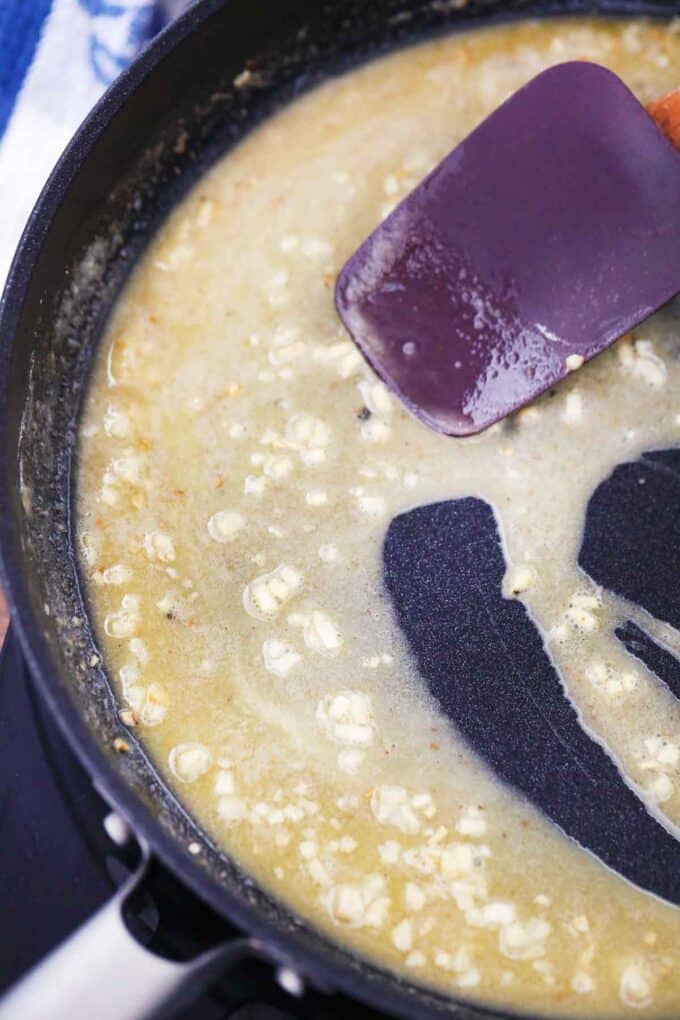 Stirring melted butter and garlic in a skillet.