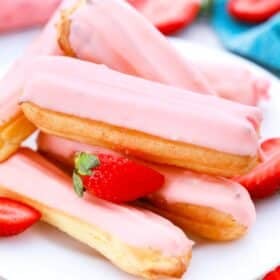a stack of strawberry eclairs on a plate and sliced fresh strawberries
