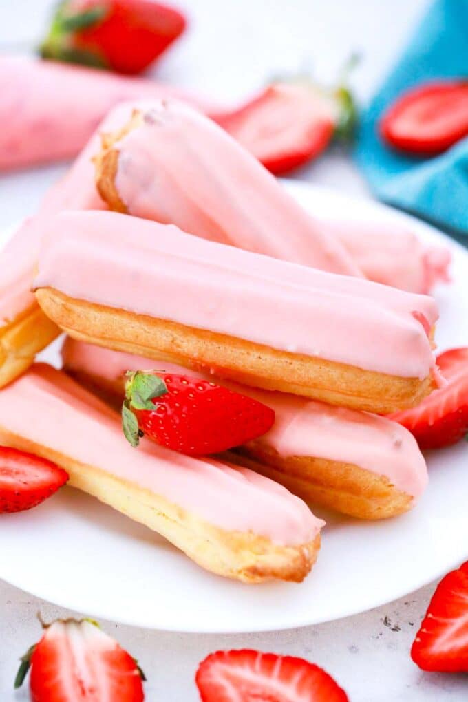a stack of strawberry eclairs on a plate and sliced fresh strawberries