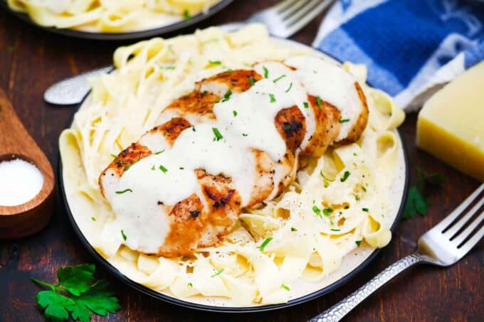 olive garden chicken alfredo dish of sliced chicken breast with alfredo sauce on top on a pile of pasta in the sauce