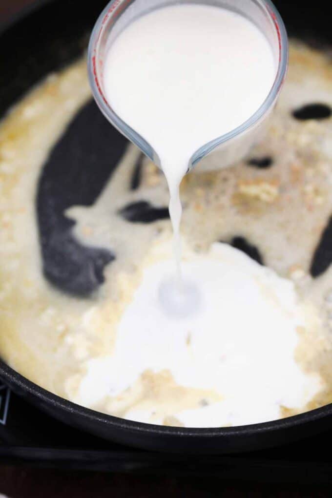 Adding cream to melted butter and garlic mixture in a skillet.