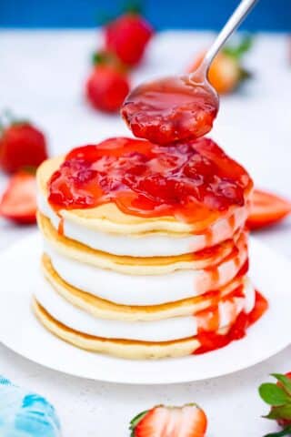 adding strawberry sauce to pancakes with cheesecake filling