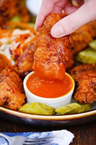 dipping nashville hot chicken in a red sauce
