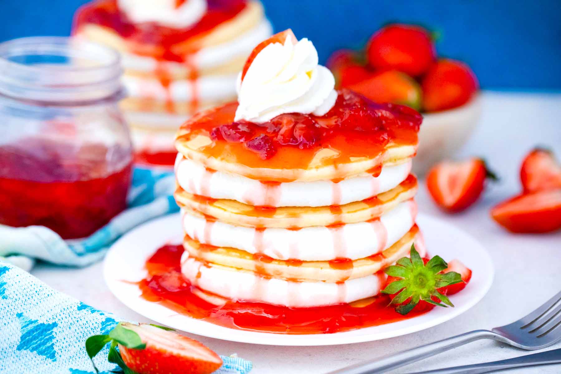 strawberry pancakes with cheesecake filling and topped with strawberry sauce and whipped cream