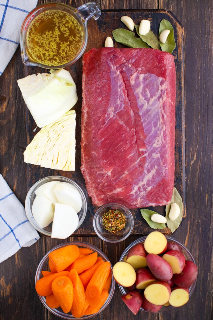 Overhead shot of Instant Pot corned beef and veggies ingredients arranged on a wooden table.