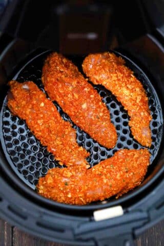 chicken tenders covered in a chips mixture in the air fryer basket