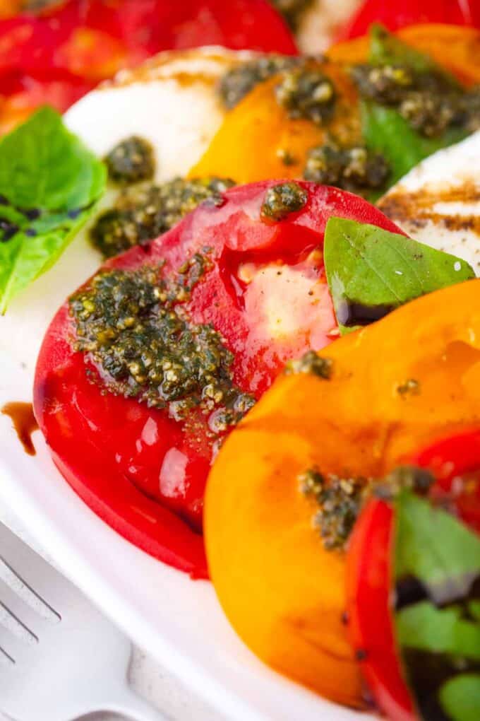 juicy heirloom tomato caprese salad topped with pesto