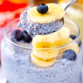 a spoonful of butterfly pea cheesecake chia pudding topped with banana