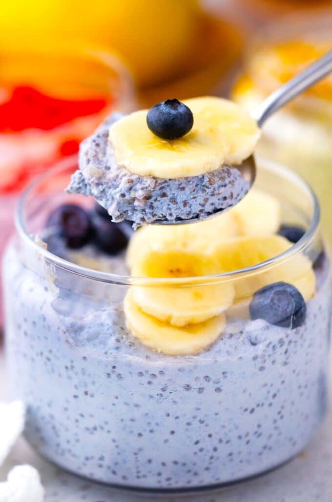 a spoonful of butterfly pea cheesecake chia pudding topped with banana