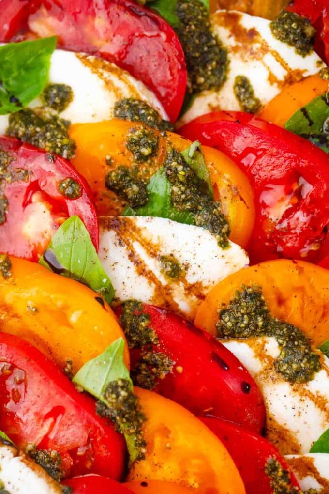 caprese salad with orange and red tomatoes, pesto, and fresh basil