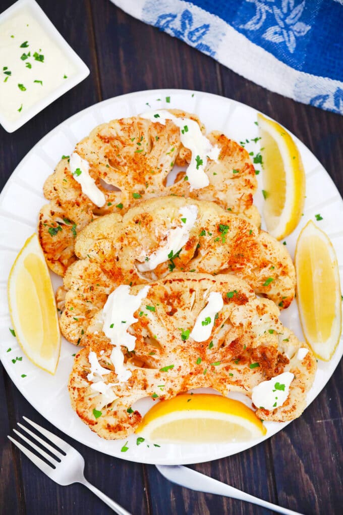 Golden brown cauliflower steak served with lemon slices.