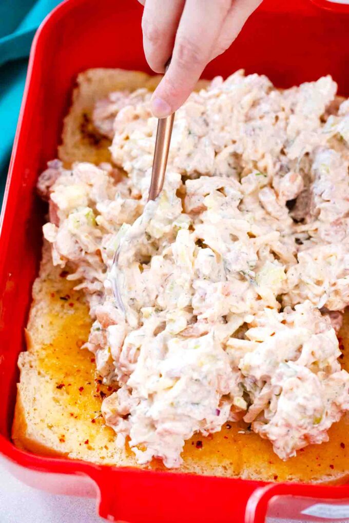 spreading shrimp salad mixture on the bottom part of a pack of hawaiian rolls