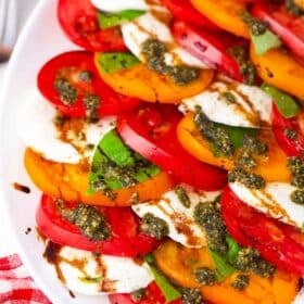 caprese salad made with orange and red heirloom tomatoes, fresh mozzarella, basil and pesto