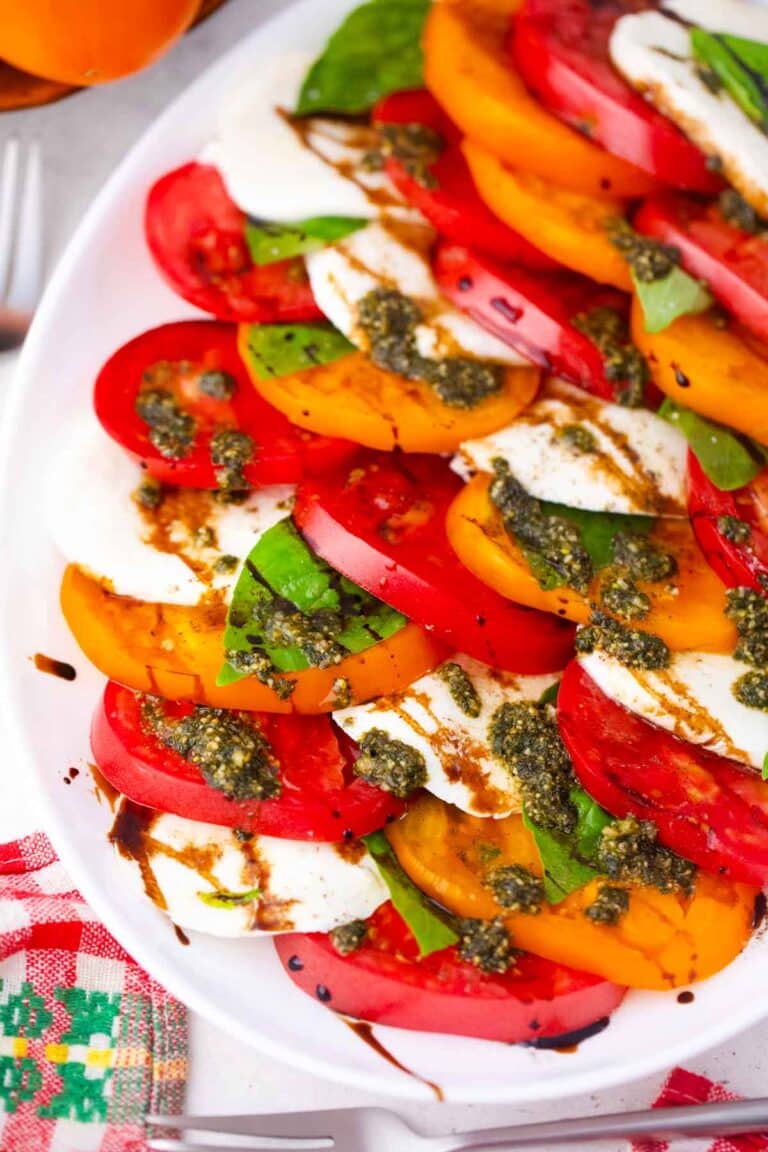 caprese salad made with orange and red heirloom tomatoes, fresh mozzarella, basil and pesto