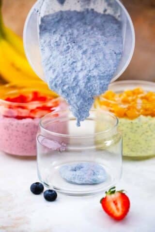 pouring butterfly pea cheesecake chia pudding in a jar