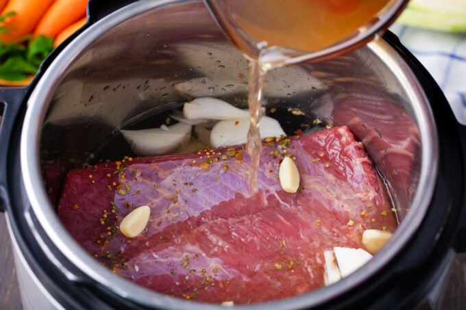 Adding Instant Pot corned beef ingredients to the inner pot.