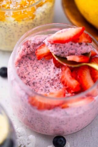 a spoonful of strawberry cheesecake chia pudding topped with fresh sliced strawberries