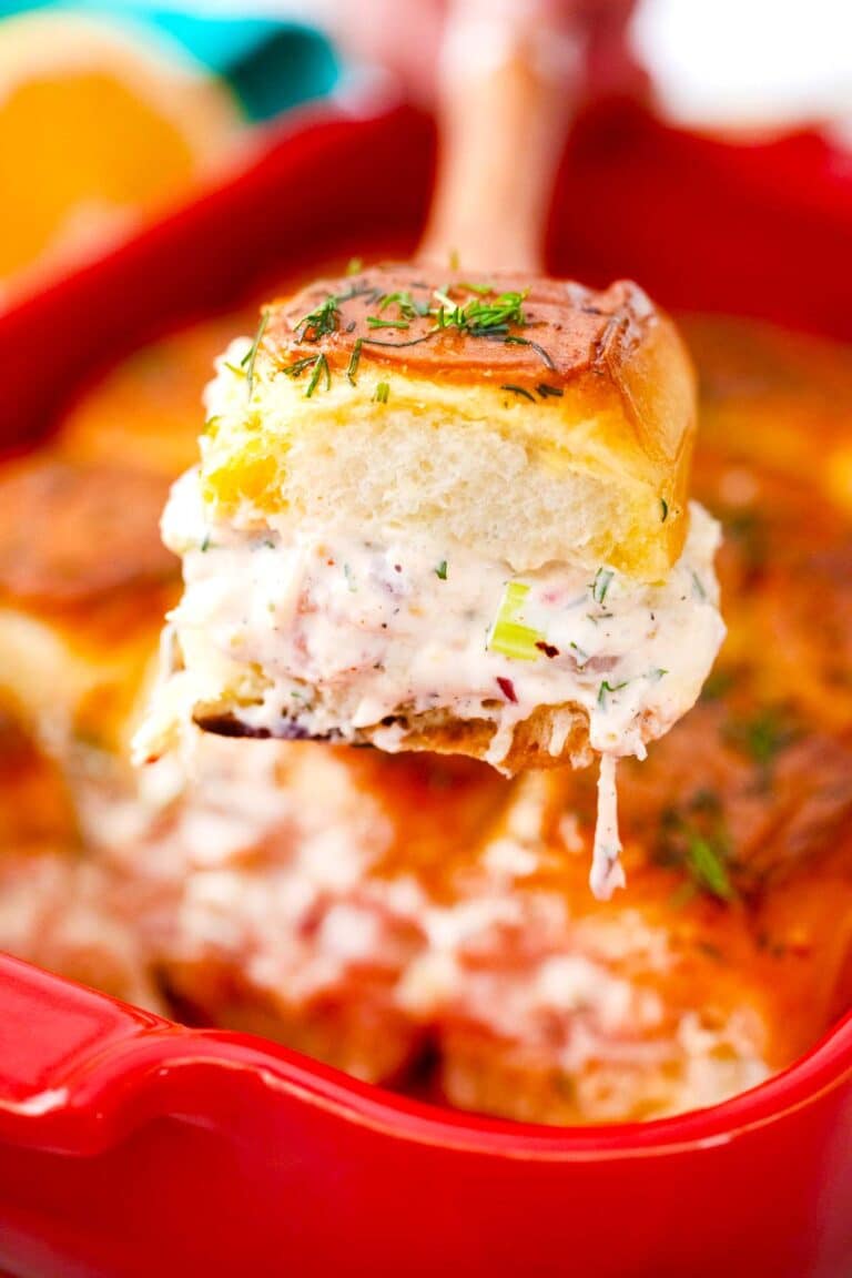 shrimp salad sliders in a baking pan and a serving spatula holding one