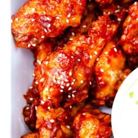close overhead show of crispy spicy korean chicken wings with an white sauce next to them