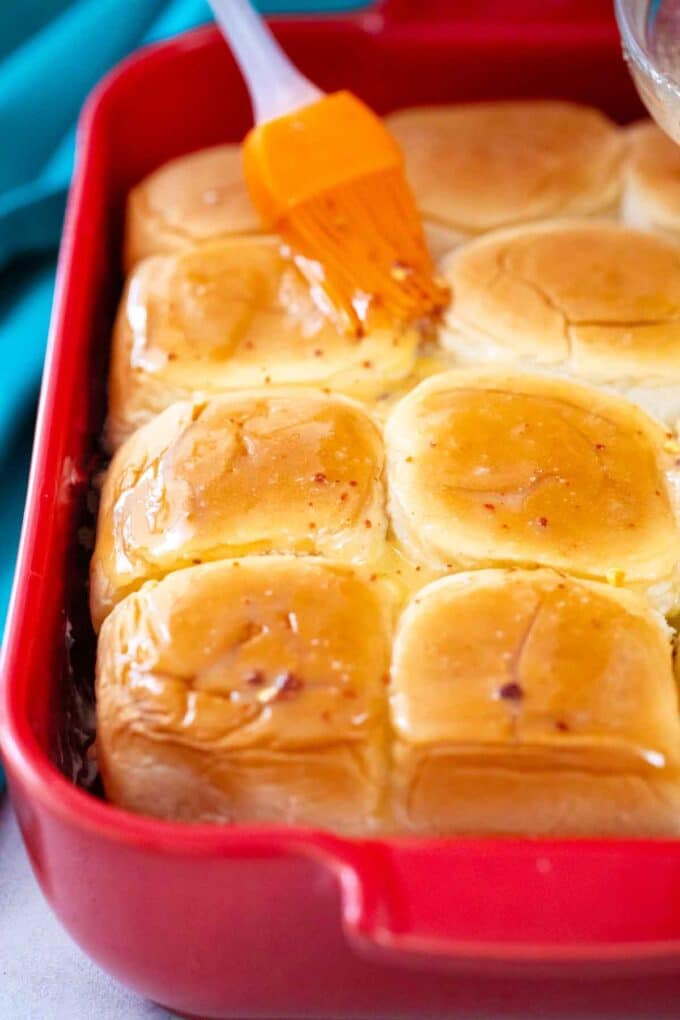 brushing with butter the top of Hawaiian rolls