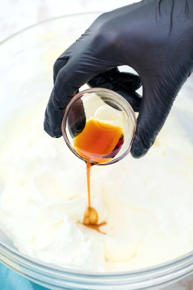 pouring vanilla extract into cream cheese mixture