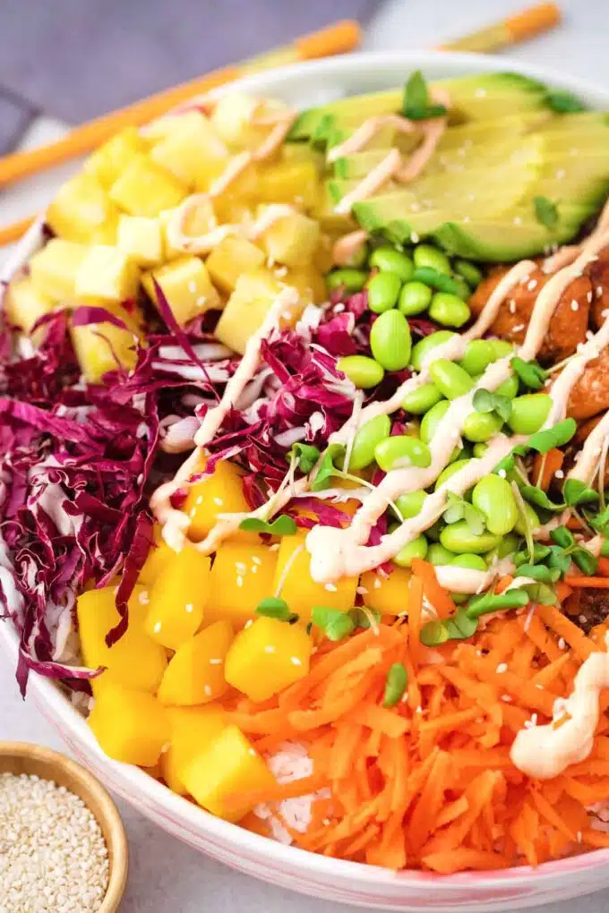 cooked salmon poke bowl with shredded red cabbage shredded carrot edamame pineapple mango