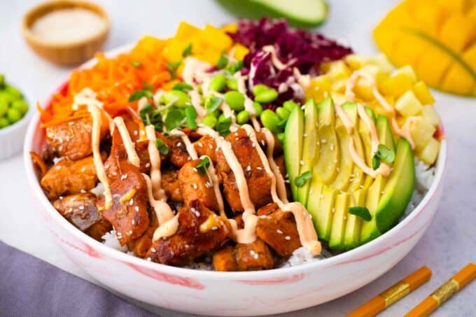 cooked salmon poke bowl with shredded red cabbage shredded carrot edamame pineapple mango and avocado