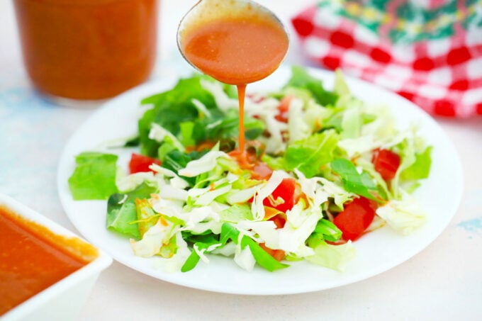 Drizzling Catalina dressing over a green salad.