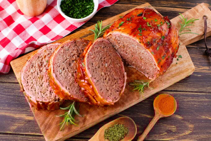 Overhead shot of sliced bacon wrapped meatloaf on a cutting board.