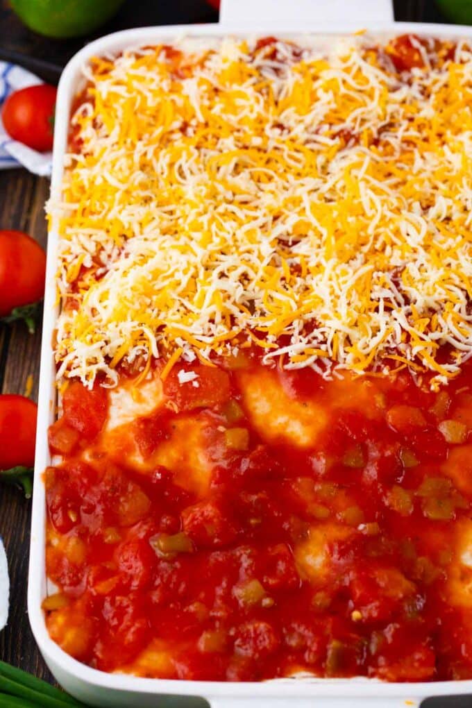 Topping taco lasagna with salsa and shredded cheese.