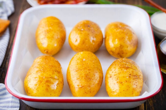 Six potatoes in a baking dish before baking.