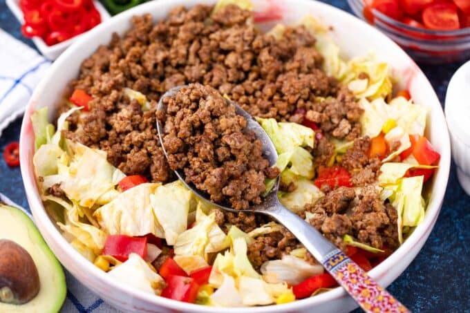 Adding taco seasoned ground beef to a bed pf lettuce.