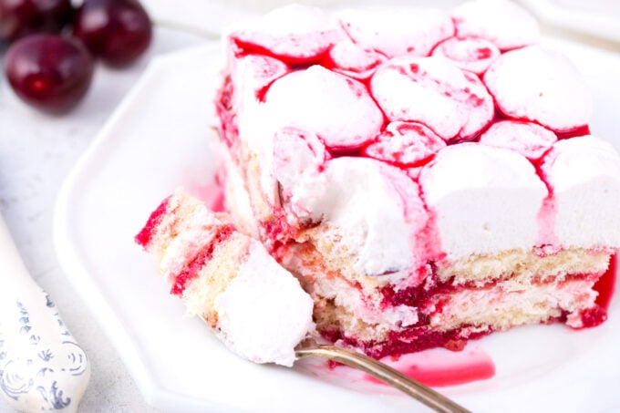 A slice of cherry amaretto tiramisu topped with cherry sauce.