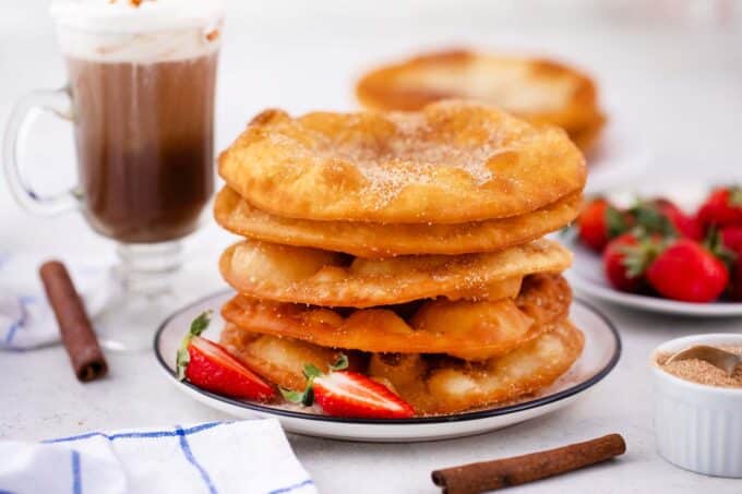 a stack of bunuelos with fresh strawberries and hot chocolate