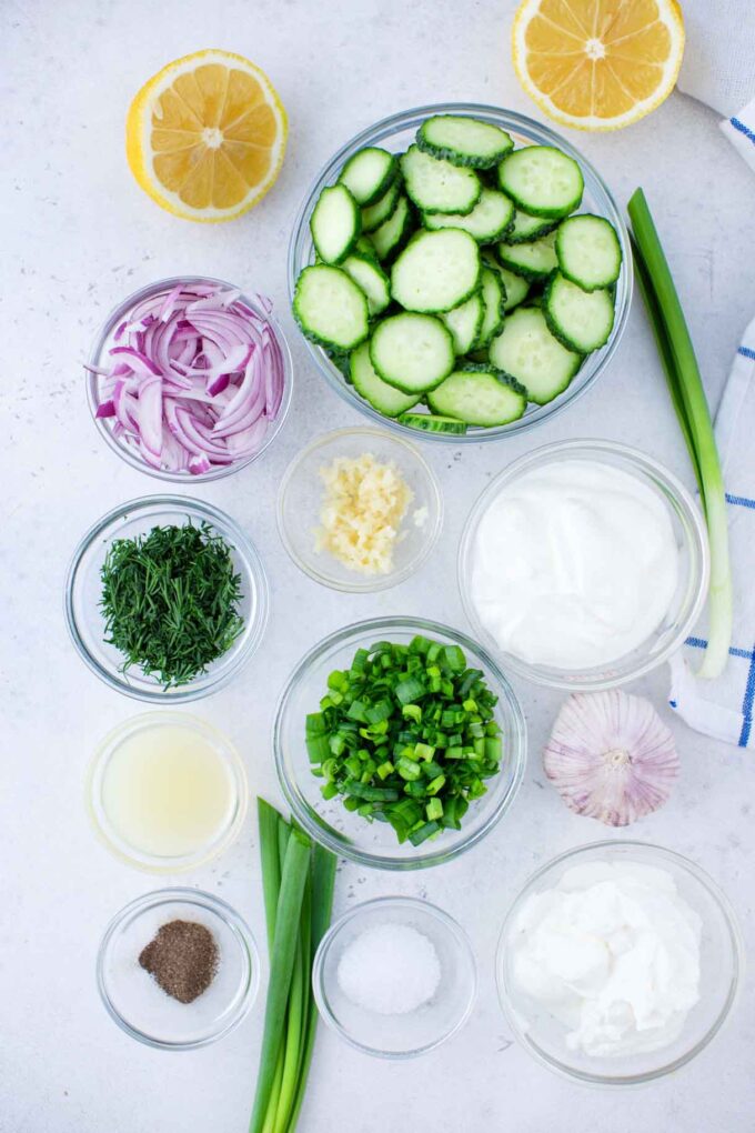 creamy cucumber salad ingredients in bowls on a table