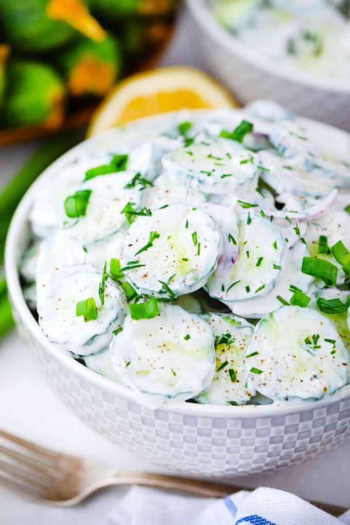 a bowl of creamy cucumber salad topped with dill and chives