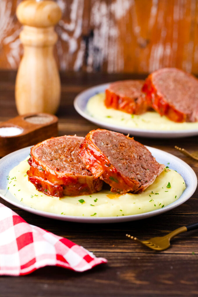 Sliced bacon wrapped meatloaf served with mashed potatoes.