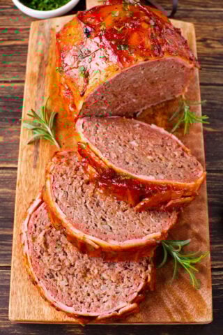 Juicy bacon wrapped meatloaf slices on a cutting board.