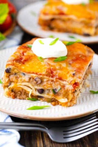 A slice of cheesy taco lasagna topped with crema fresco.
