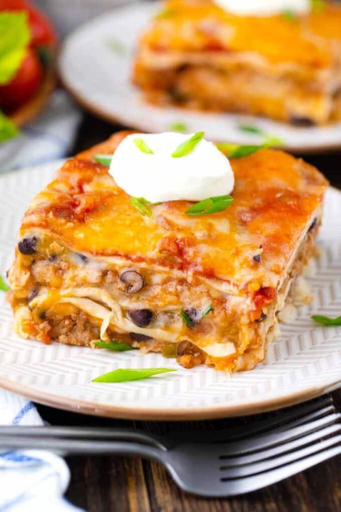 A slice of cheesy taco lasagna topped with crema fresco.