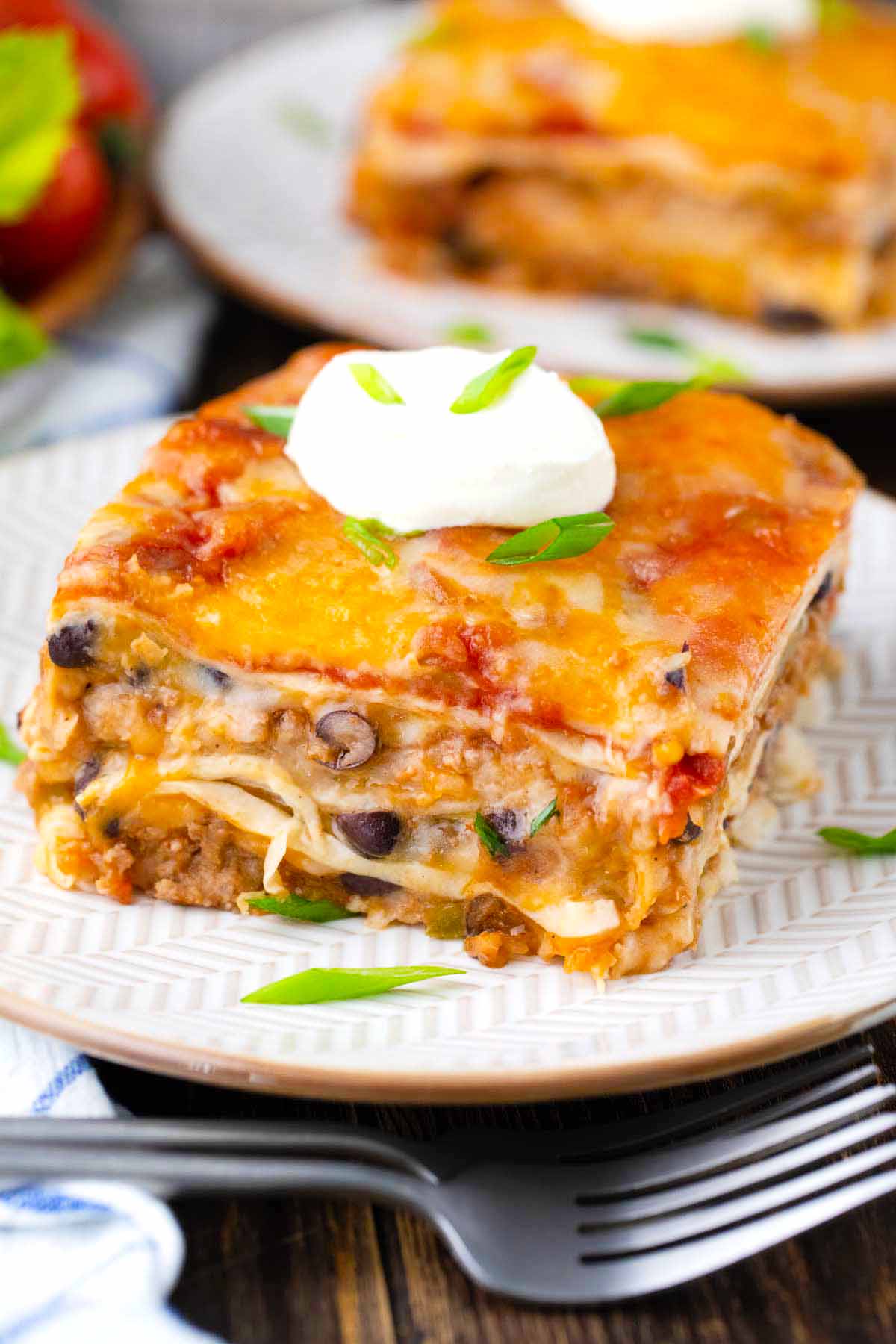 A slice of cheesy taco lasagna topped with crema fresco.